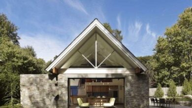 Nowa architektoniczna willa z dużym oknem, otoczona zielenią, idealna do relaksu i odpoczynku w naturze.