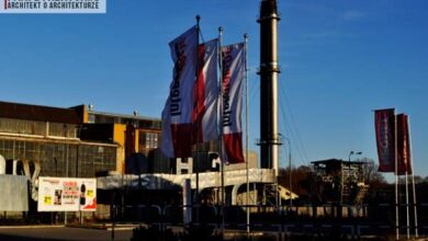 Przemysłowa hala z flagami firmy PaniDyrektor.pl na tle niebieskiego nieba, symbolizująca profesjonalizm i innowacyjność w branży architektonicznej i architektury.