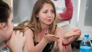 Kobieta prowadząca warsztaty lub szkolenie, rozmawiająca i angażująca uczestników, w nowoczesnym otoczeniu, promująca rozwój i edukację, profesjonalne szkolenia i konsultacje dla firm.