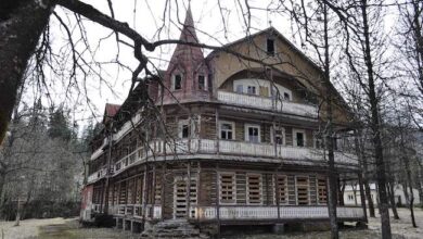 Staroświecki dom z drewna i bala, otoczony drzewami, w stylu rustykalnym, w otoczeniu natury, z balkonami i wieżyczkami, idealny do wypoczynku na łonie natury.