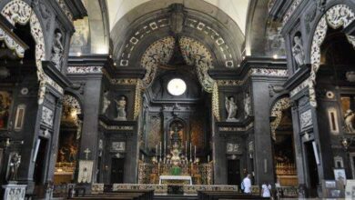 Ciemne, bogato zdobione wnętrze kościoła z ołtarzem i detalami architektonicznymi w stylu barokowym, idealne do promocji usług architektonicznych i remontowych.