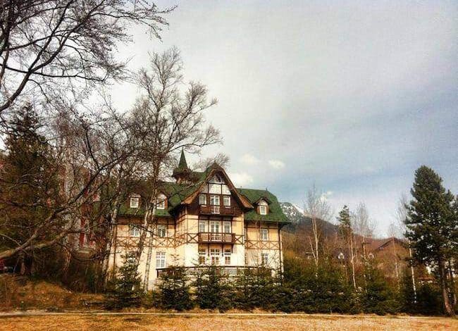 Klasyczny dom w stylu góralskim z panoramicznym widokiem na góry i okoliczne lasy, idealny na wypoczynek w otoczeniu natury.