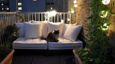 Przytulna balkonowa przestrzeń do relaksu z wygodną kanapą, oświetleniem i zielonymi roślinami, idealna do odpoczynku i spędzania czasu na świeżym powietrzu w mieście.