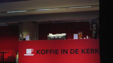 Kawiarnia w kształcie mównicy z napisem "KOFFIE IN DE KERK" w czerwonej kolorystyce, nowoczesny design, idealne miejsce na spotkania i relaks przy kawie, architektura i projekty wnętrz optima.