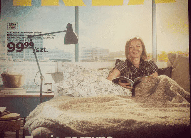 IKEA łóżko z pościelą i kobietą czytającą książkę w sypialni, promująca komfort i aranżację wnętrz, idealne rozwiązanie dla domowych sypialni, które inspirują do rozpoczęcia dobrego dnia.
