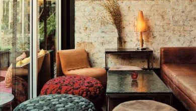 Przytulny salon z wygodnymi sofami i unikalnymi pufami, nowoczesny wystrój wnętrz, ciepłe oświetlenie, dekoracje z natury, relaks i komfort w eleganckim otoczeniu.