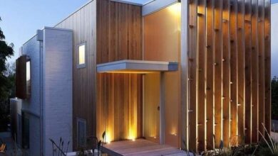 Nowoczesny dom z drewnianymi elewacjami i efektownym oświetleniem fasadowym, idealny dla miłośników architektury i designu, optymalny wybór dla funkcjonalności i estetyki.