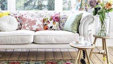 Kolorowa sofa w stylu skandynawskim z dekoracyjnymi poduszkami i kwiatami w naturalnym świetle, idealne do aranżacji wnętrz w optymalnym stylu.