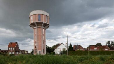 Liczba wodna w mniejszym zupełnie miejscu na tle nieba z ciemnymi chmurami, nowoczesny zbiornik wodny, przemysłowa architektura, otoczony domami jednorodzinnymi, obszar wiejski, relaksująca krajobrazowa sceneria, przestrzeń na tle natury.