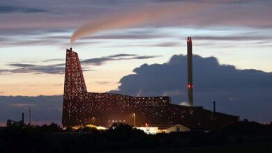 "Elektrociepłownia emitująca dym podczas zachodu słońca z przemysłowymi kominami".