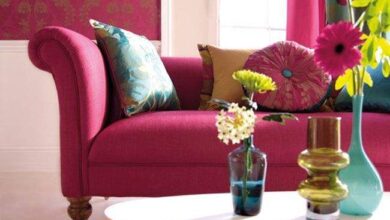 Kolorowa stylowa przestrzeń z różową sofą i kwiatami w szklanych wazonach, idealne rozwiązanie dla wnętrz w stylu optima, eleganckie i funkcjonalne, do domu lub biura.