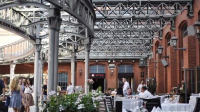 Nowoczesna restauracja na świeżym powietrzu z industrialnym stylem, duża przestrzeń, dekoracje kwiatowe, idealne miejsce na imprezy i spotkania biznesowe w sercu miasta.