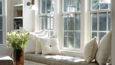 Komfortowa poduszka na okiennym siedzeniu w jasnym wnętrzu, naturalne światło, wnętrze domowe, relaks, styl skandynawski, przestrzeń do odpoczynku, aranżacja wnętrza, PaniDyrektor.pl, optymalne rozwiązania dla domu, elegancki i przytulny wystrój.