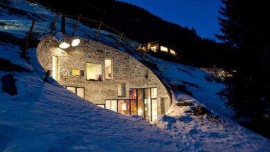 Nowoczesny domek górski w ośnieżonym krajobrazie, luksusowa architektura na zboczu góry, przytulne wnętrza, idealny dla miłośników wypoczynku w górach i unikalnego designu.