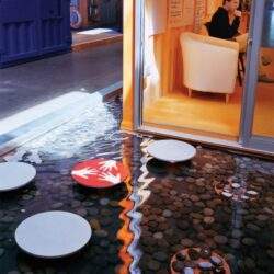 Spokojne biuro z przeszkloną ścianą, wygodnymi fotelami i kreatywną atmosferą, idealne do pracy i spotkań biznesowych. Otoczenie sprzyja koncentracji i relaksowi w inspirującym środowisku.