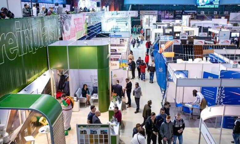 Przemysłowa hala targowa z stoiskami wystawców i zwiedzającymi podczas wydarzenia branżowego. Nowoczesne ekspozycje i prezentacje produktów w dynamicznej atmosferze konferencji i targów.