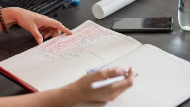 Notatnik z zapisami, długopis, telefon i woda na biurku w biurze, praca i planowanie, inspiracja do organizacji i rozwoju osobistego, kreatywność i skuteczne zarządzanie czasem, tematyka edukacyjna i biznesowa.