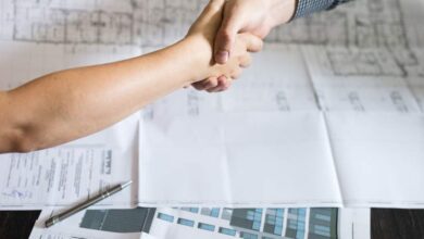 Profesjonalne uścisk dłoni, podpisanie umowy, współpraca biznesowa, dokumenty i plany architektoniczne na stole, zlecenie optymalnych rozwiązań dla firm.