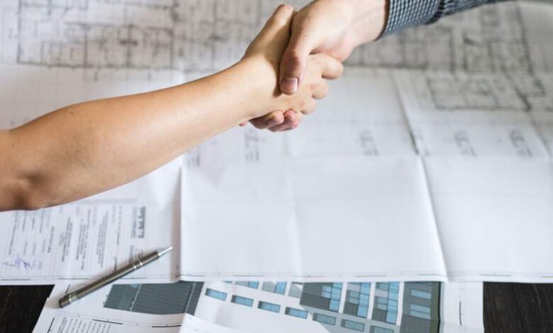 Profesjonalne uścisk dłoni, podpisanie umowy, współpraca biznesowa, dokumenty i plany architektoniczne na stole, zlecenie optymalnych rozwiązań dla firm.