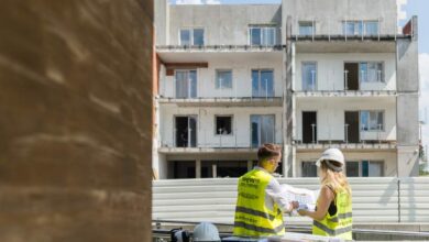 Pracownicy na budowie rozmawiają nad projektami przed rozpoczęciem prac przy nowoczesnym budynku mieszkalnym.