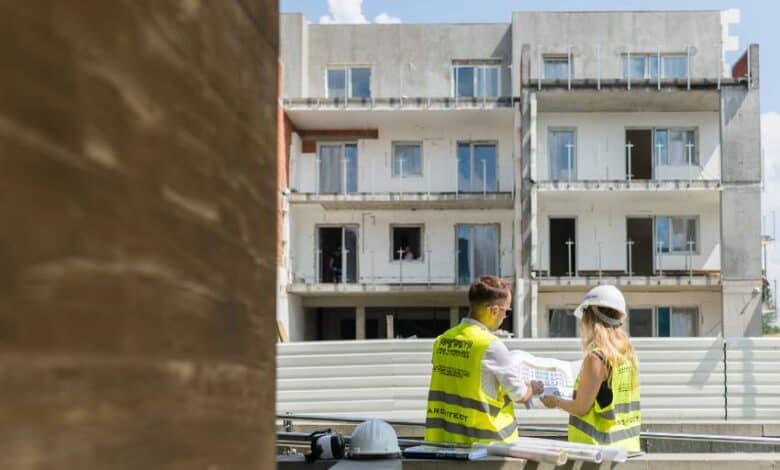 Pracownicy na budowie rozmawiają nad projektami przed rozpoczęciem prac przy nowoczesnym budynku mieszkalnym.