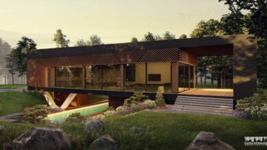 Nowoczesny dom z dużymi przeszkleniami i tarasem, otoczony zielenią i kamieniami, idealny do relaksu i wypoczynku na łonie natury, projekt architektoniczny od Urban Project Architecture.