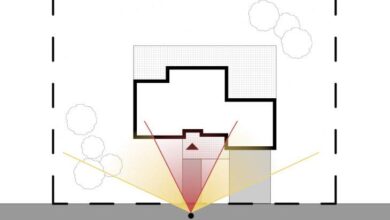 Widok z drona na wejście do domu z oświetleniem i otoczeniem. Żywy plan ogrodu, drzewa i podjazd z podświetleniem na przednim fragmencie posesji. Projekt architektoniczny domu i podjazdu.