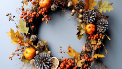 Kolorowy jesienny wianek z jarzębiną, gałęziami, liśćmi, szyszkami i owocami na niebieskim tle, idealny do dekoracji sezonowej, na drzwi lub ścianę, inspirowany naturą.